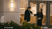 a man in a tuxedo shakes hands with a woman in a black dress in front of a building that says nbc