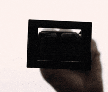 a person is holding a black object in their hand with a white background