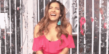a woman in a pink off the shoulder dress is laughing .