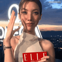 a woman in a white top is holding a red elle magazine