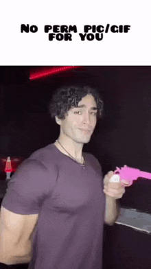 a man is holding a pink gun in his hand .