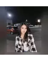 a woman in a plaid shirt is standing in a parking lot at night