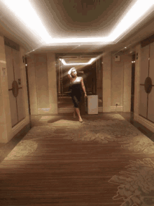 a woman stands in a hallway with a sign that says ' emergency exit '