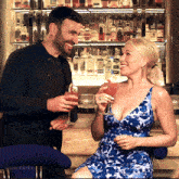 a man and a woman are sitting at a bar with bottles of vodka on the shelves behind them