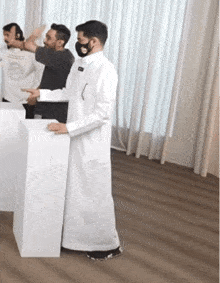 a man wearing a mask is standing in front of a white podium