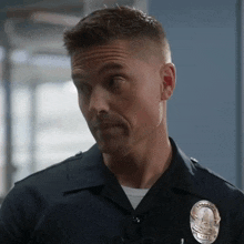 a man in a police uniform with a badge on his chest is making a funny face .