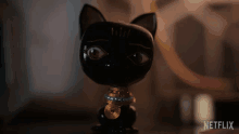 a statue of a black cat with the word netflix on the bottom left