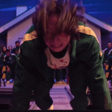 a man in a green jacket is crying in front of a crowd .