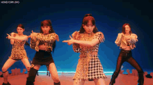 a group of girls are performing a dance in front of a blue background with the words honeycam.org on the bottom