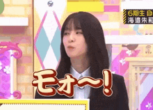 a woman in a suit is making a funny face while standing in front of a pink wall .