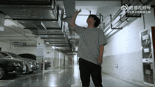 a man in a grey shirt is standing in a dimly lit underground parking garage