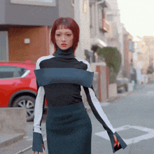 a woman with red hair is walking down a street wearing a turtleneck and skirt