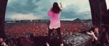 a woman in a pink shirt is standing on a stage in front of a crowd at a concert .