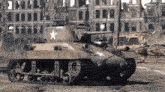 a tank with a star on the side is driving in front of a destroyed building .