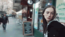 a woman is standing in front of a store with a sign that says open hour
