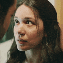 a close up of a woman 's face with a man behind her