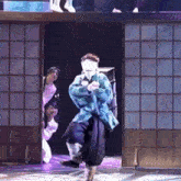a man in a blue jacket is dancing on stage