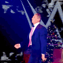 a man in a purple suit and tie is dancing in front of a christmas tree
