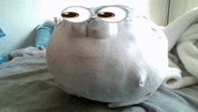 a stuffed animal with big googly eyes is sitting on a bed