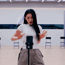 a woman in a white shirt is standing in front of a microphone with the word swirls on the bottom right