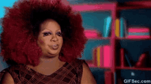 a woman with a big red afro is making a funny face .