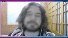 a man with long hair and a beard is talking on a video call .
