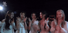 a group of girls are standing next to each other in front of a microphone and clapping their hands .