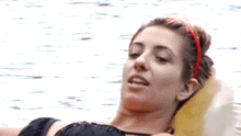a woman with a red headband is laying on a yellow raft in the water