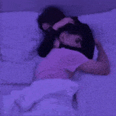 a man in a pink shirt is hugging a woman in a black shirt while laying in bed .