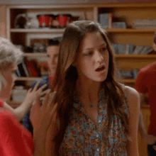 a woman in a blue floral shirt is standing in front of a man in a red shirt
