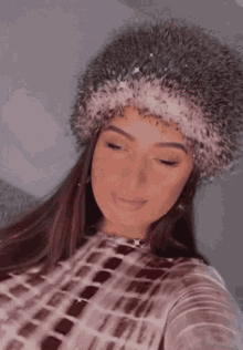 a woman wearing a fur hat is taking a picture of herself .