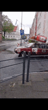 a red car with a fire extinguisher on top of it is parked in front of a building with the word kazimierz on it