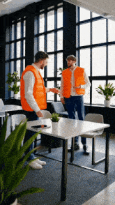 two men in orange vests are standing next to each other