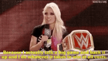 a woman is holding a microphone and talking into it while holding a wrestling championship belt .