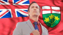 a man in a suit stands in front of a british flag