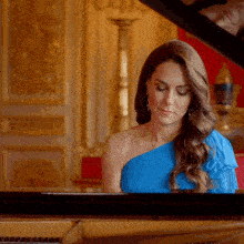 a woman in a blue dress is sitting at a piano