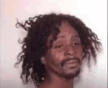 a man with long curly hair and a beard is looking at the camera .