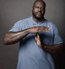 a man wearing a blue shirt is making a stop sign with his hands