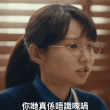 a woman wearing glasses and a blue shirt with chinese writing on her face