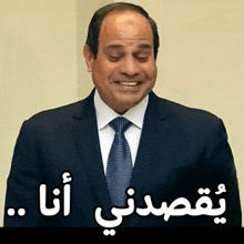 a man in a suit and tie is smiling with arabic writing behind him ..