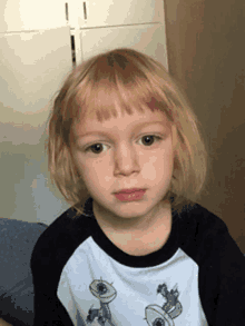 a young boy with blonde hair is wearing a black and white t-shirt with aliens on it