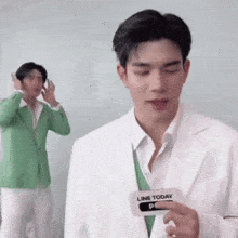 a man in a green suit is standing next to a man in a white suit holding a name tag .