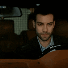a man in a suit is driving a car