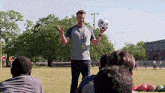 a man is holding a soccer ball in his hand while talking to a group of children .