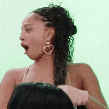 a woman wearing a heart shaped earring is getting her hair done .