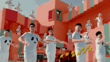 a group of men wearing panda shirts are dancing in front of a red car