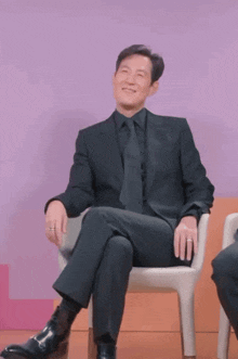 a man in a suit and tie is sitting in a chair