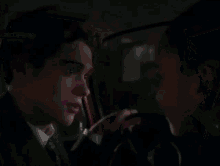 a man and a boy are sitting in a car and looking at each other .