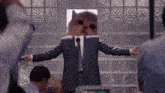 a man in a suit with a cat on his head giving a speech