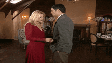 a man in a suit and a woman in a red dress are standing next to each other